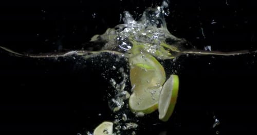 Slices of Lime Falling Into the Water with Air Bubbles.