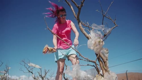 Mujer activista voluntaria recoge bolsas de plástico de un árbol muerto en Hawái