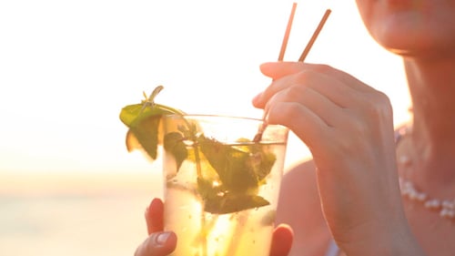 Woman Drinks Mojito on Beach at Sunset