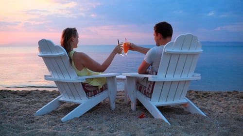 Couple Toasting Cocktails on Beach at Sunset