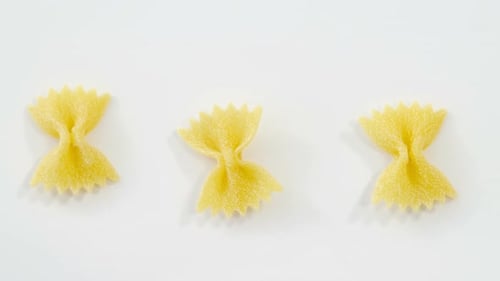 Row of bow tie pasta on white background
