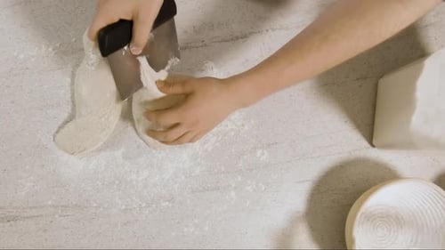 Top-Down-Aufnahme von Young Male Chef, der Sauerteigteig auf einer Küchenseite formt und in eine Bank legt