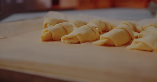 Raw Croissants Being Arranged on a Baking Sheet