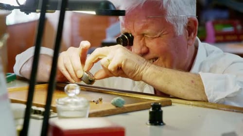 Gray Haired Man Inspecting Watch at Workstation