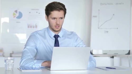 Frustrated Man Working at Office Desk on Laptop