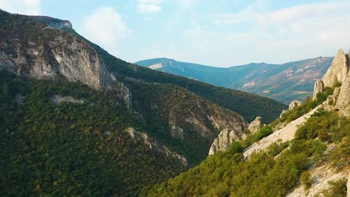 Aerial flyby backwards in mountain range discover rocky steep peaks