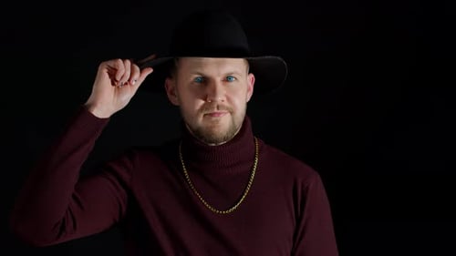 Facial Expression of Handsome Man in Stylish Hat Looking at Camera and Smiling on Black Background