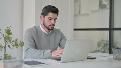 Young Man Working on Laptop in Office