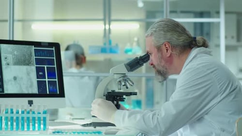 Scientist Examining Sample Through Microscope in Bright Lab