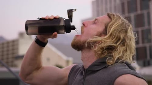 Athletic Man Drinks Water in Urban Setting