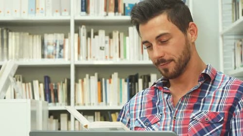 Young Adult Reading in Library With Bookshelves