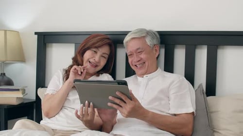 Senior Couple Enjoying Tablet in Bed at Home