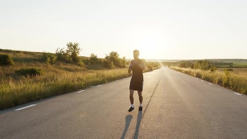 Kickboxer with Boxing Bandages Jogging and Training Kicks on Country Road