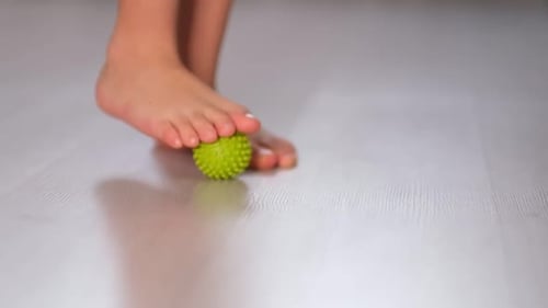 Child Massages Bare Foot with Green Ball