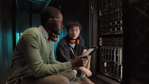 Two Men Examining Computer Hardware in Server Room