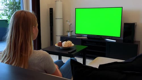 Woman Sits on Couch in Living Room, Watches TV Green Screen