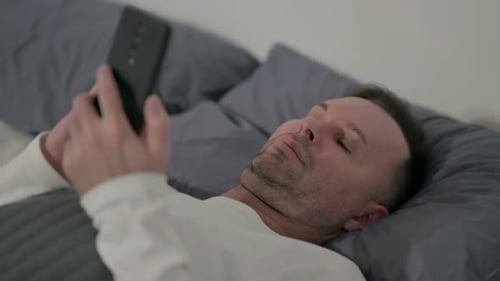 Close Up Casual Man Using Smartphone While Laying in Bed