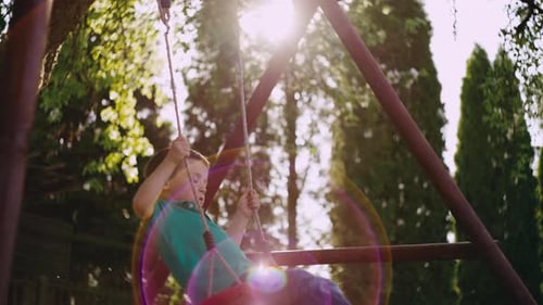 The Boy Rides on a Children's Swing