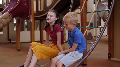Children are Sitting on the Playground on a Rope Ladder Talking and Laughing