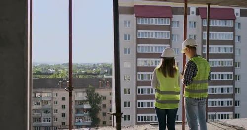 Building Workers Working at Construction Site Builders Looking in Blueprint Back View Copy Space