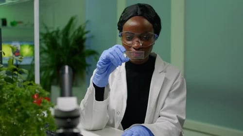 Botanist Researcher Scientist Analyzing Green Liquid Sample Under Microscope