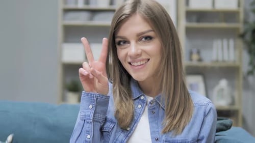 Smiling Woman Making Peace Sign Indoors