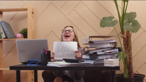 Woman office worker is sitting at table with laptop and stack of folders of documents, crying