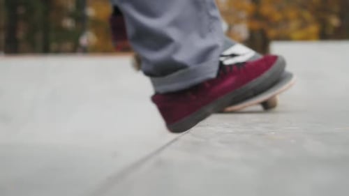 Skater Practicing in the Autumn Concrete Skate Park Making Tricks and Rides in Ramp