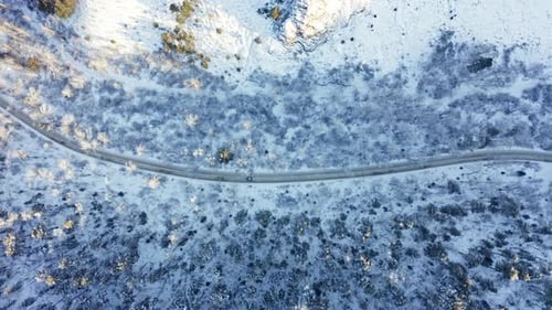 Aerial View of a Car Driving on a Mountain Winter Road