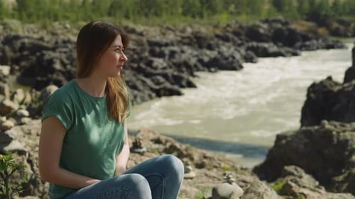 Frau sitzt im Sommer am schattigen Ufer des Narrow Mountain River