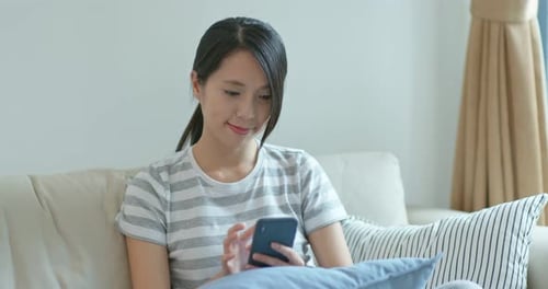 Young Woman Using Smartphone on Couch at Home