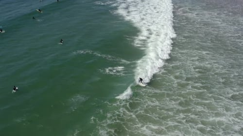 Surfer riding and turning with spray on blue ocean wave, surfing ocean. Aerial