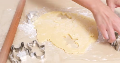 Hands Cutting Christmas Cookies from Dough