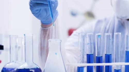 Scientist Adding Blue Liquid to Flask in Lab
