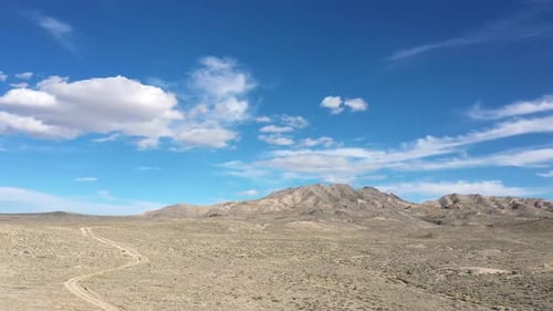 Flying backwards through gap in rocks along dirt road in the desert