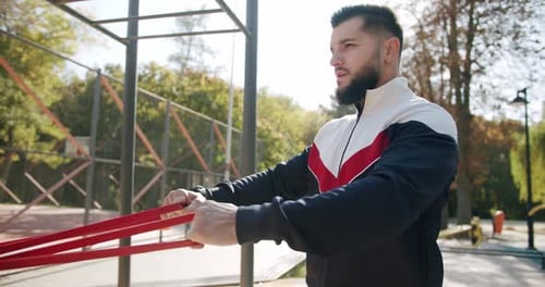 Man Exercises with Resistance Bands in Urban Park