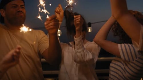 Friends celebrating together at the rooftop with sparkles at night. Shot with RED helium camera in 8