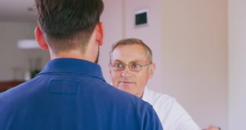A Smiling Father Shakes His Son's Hand and Gives Him a Hug