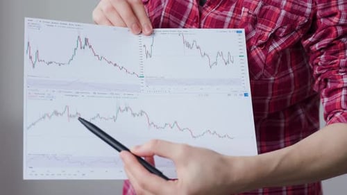 Person Points at Financial Chart with Pen