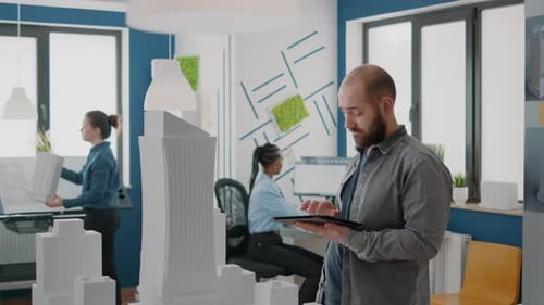 Expert Contractor Working on Building Model and Design on Digital Tablet Using Maquette on Table