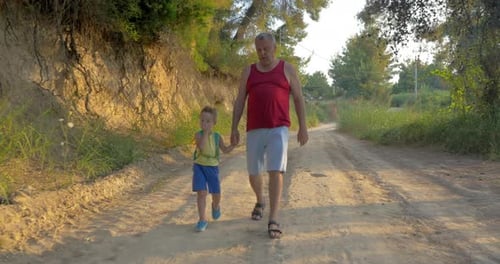 Man and Boy Walking Down Dirt Road Together