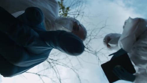 People in Suits Examine Outdoors