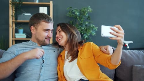 Man and Woman Taking Selfie with Smartphone Having Fun Laughing Kissing
