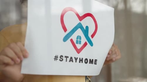 Child Holds Stay Home Sign By Window