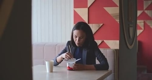 Woman Eats Takeout Lunch at Table Indoors