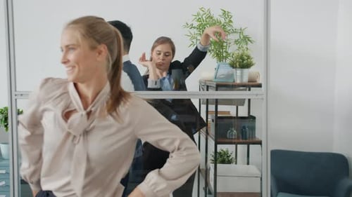 Beau mec d'âge moyen en costume dansant au bureau avec des collègues qui s'amusent au travail