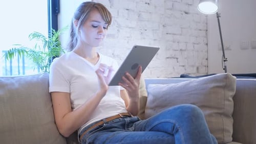 Woman Using Tablet Indoors on Sofa