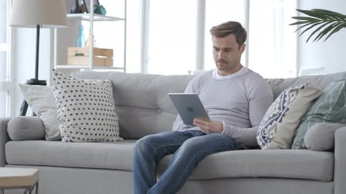 Man Using Tablet Device on Gray Couch