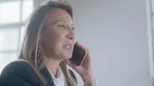Happy Businesswoman Talking on Phone While Working in Office