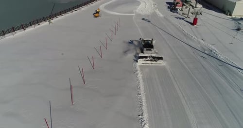 Snow Groomer Smoothing Ski Slope in Winter Aerial